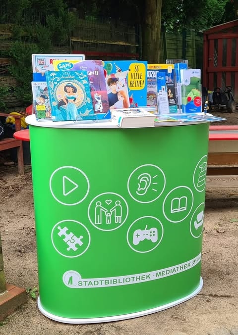 Zu sehen ist ein grüner Infostand der Stadtbibliothek Troisdorf.