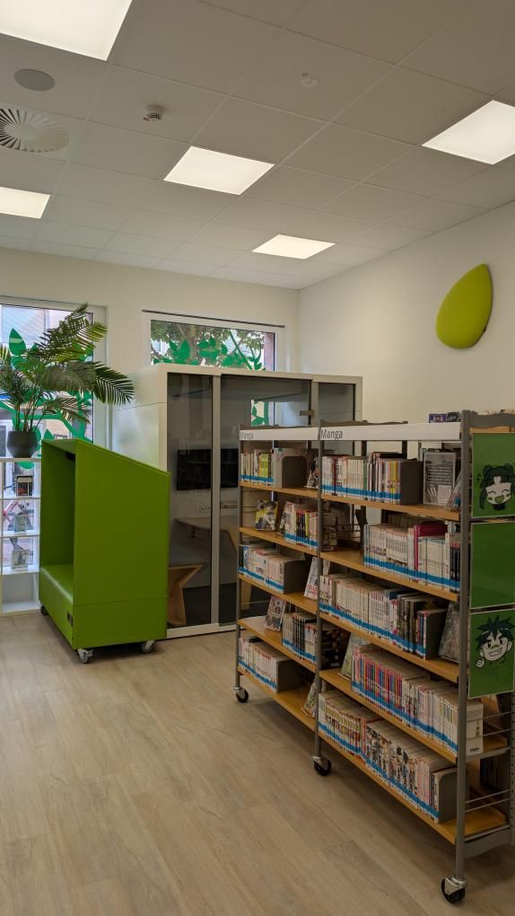 Zu sehen ist ein Teil des Jugendbereichs der Bibliothek. Ein Manga-Bücher Regal und verschiedene Sitz und Lernmöglichkeiten.