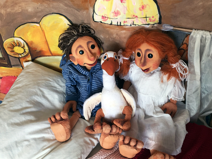 Auf dem Bild sind zwei Puppen und eine Puppe einer Gans zu sehen. Sie gehören zu dem Puppentheaterstück "Die Weihnachtsgans Auguste"