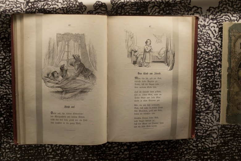 Aufgeschlagenes Buch mit schwarz-weiß Zeichnungen von Kindern beim zubett gehen mit Gebeten oder Gedichten