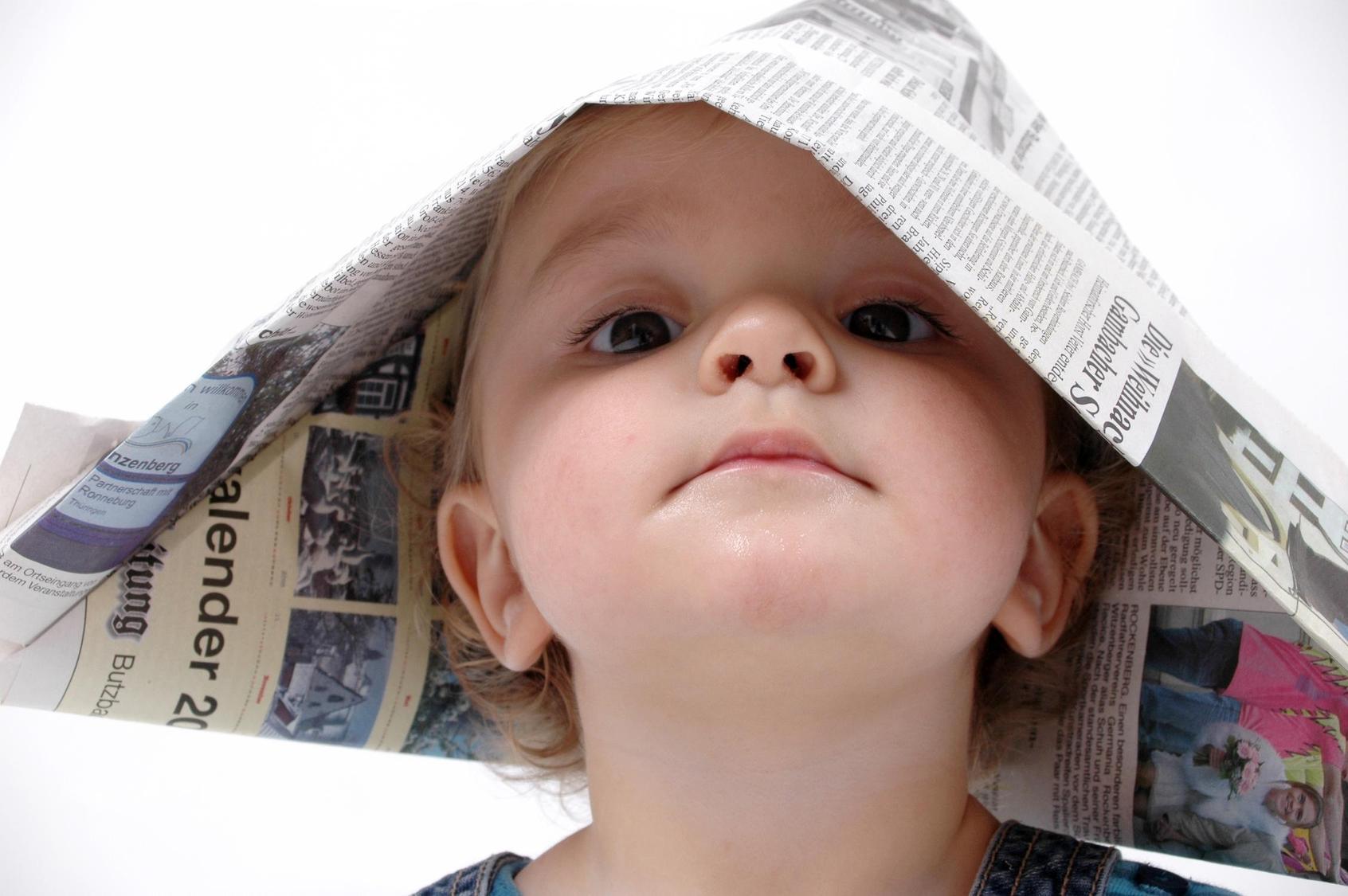 Kind mit Hut aus Zeitungen