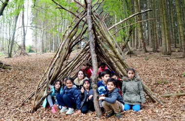 Kinder in einem selbst gebauten Tipi aus Ästen