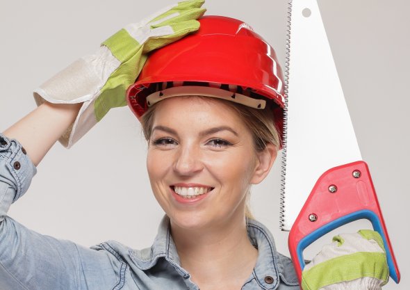 Frau mit Schutzhelm und Säge