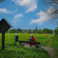 Ein Mann sitzt auf einer Bank und schaut auf Altenrath