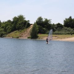 Surfer auf dem Rotter See vor der Liegewiese am Badestrand