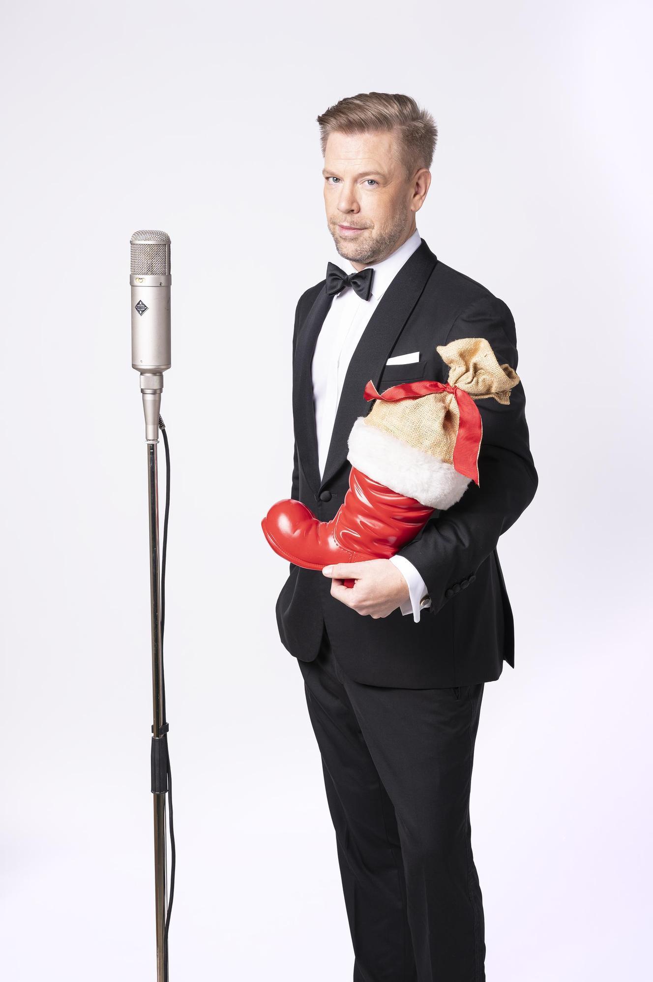 Tom Gaebel vor einem Mikrofon auf Stativ mit einem gefüllten Nikolausstiefel auf dem Arm