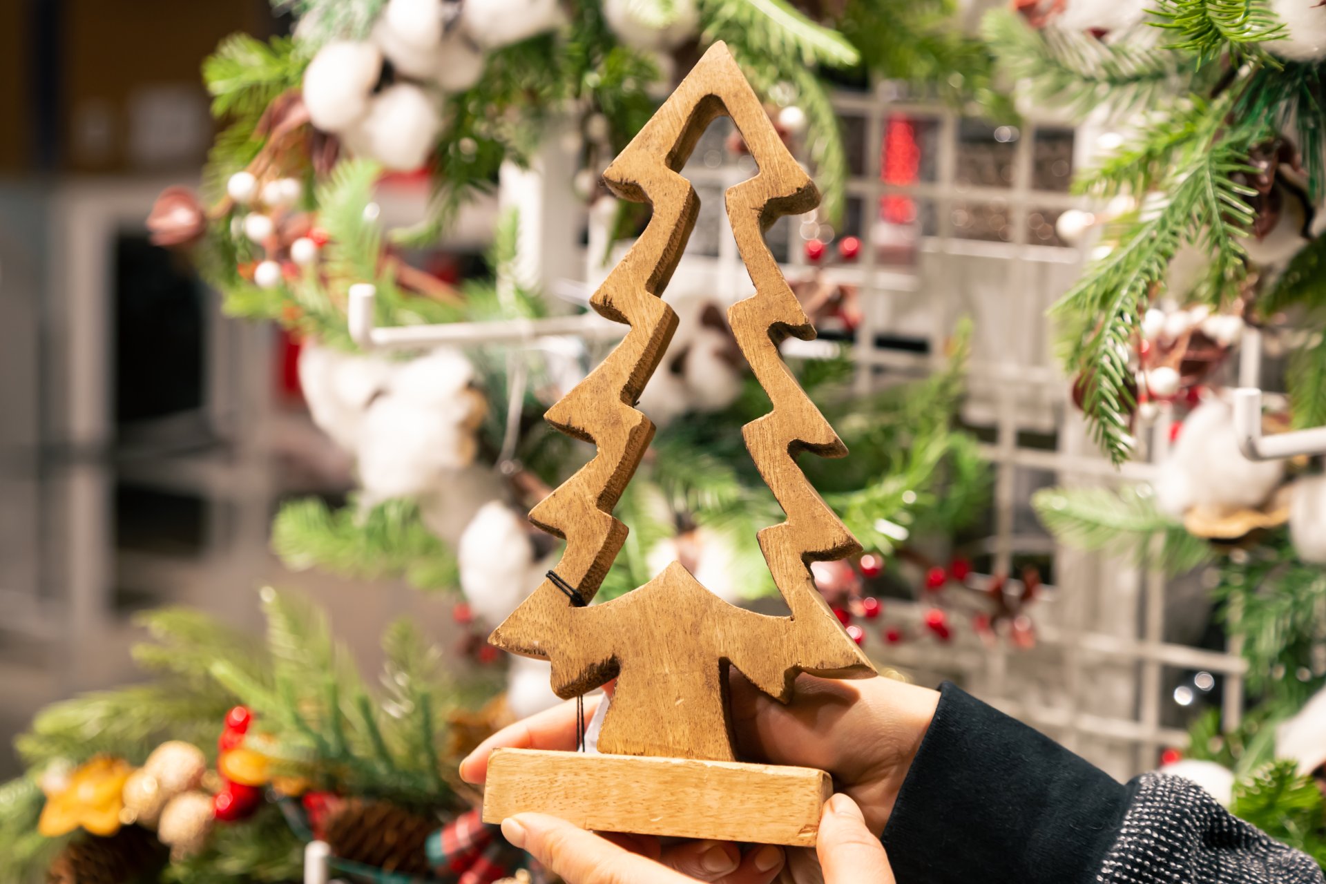 A woman holds a wooden decorative Christmas tree in her hands in a store.