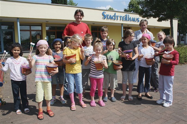 Auftritt mit selbst gemachten Trömmelchen: Manuel Juttner und Stadtteilhaus-Koordinatorin Britta Samanns mit den jungen musikbegeisterten Besuchern des Stadtteilhauses.