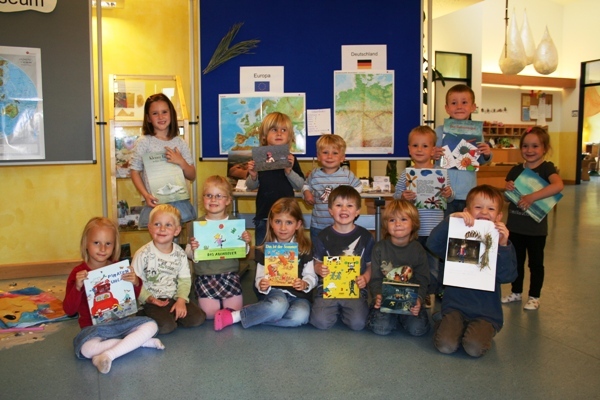 Die Kinder des Familienzentrums mit ihren Lieblingsbüchern vor den ausgestellten Schätzen aus Deutschland und Europa