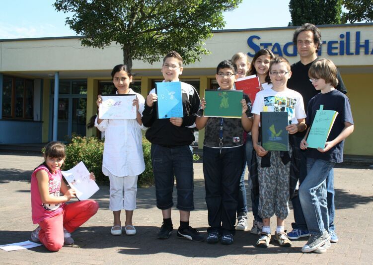 Eigene Bücher phantasievoll gestaltet: Troisdorfer Kinder mit dem Künstler Kazem Heydari vor dem Stadtteilhaus FWH.