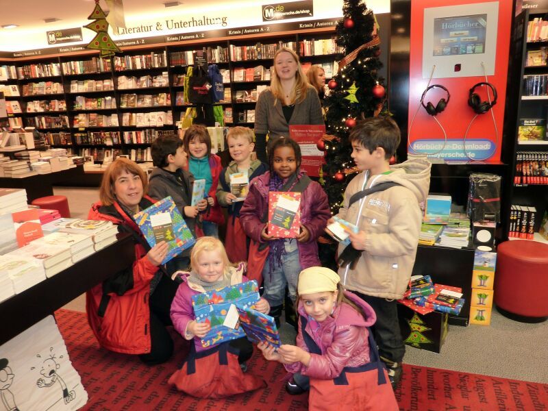 Freudestrahlend zwischen Büchern: Kinder aus dem Familienzentrum Kita Daimlerstraße mit ihrer Kita-Leiterin Beate Hecht (links) in der Mayerschen Buchhandlung.