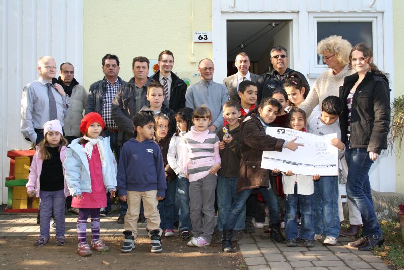 Große Freude über großen Scheck: Claudia Hoffmann (2.v.r.) mit Vertretern aus Wohnungsbau Genossenschaft und Handwerkbetrieben sowie Kindern vor dem Haus International.