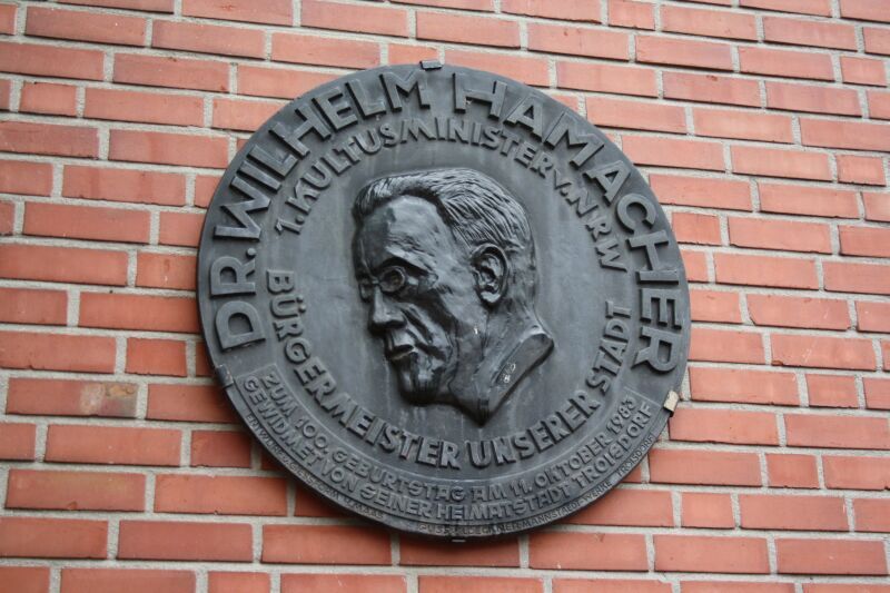 Eine gusseiserne Tafel erinnert an Dr. Wilhelm Hamacher, NRW-Kultusminister und Troisdorfer Bürgermeister.