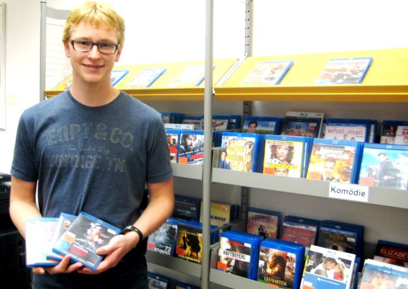 Pascal Biber vor den Blu-ray Discs ist zurzeit FSJler in der Stadtbibliothek.