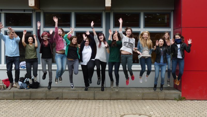 Lehrer Chris Bonus (links) mit den Teilnehmerinnen seines Kunstprojekts geradewegs "jumping in the past"