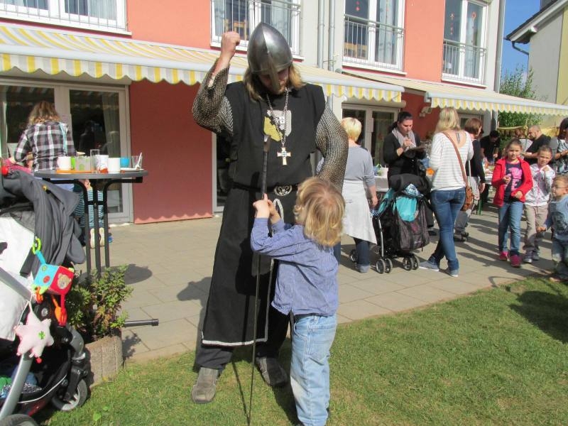 Mann mit Ritterkostüm zeigt Kind sein Schwert