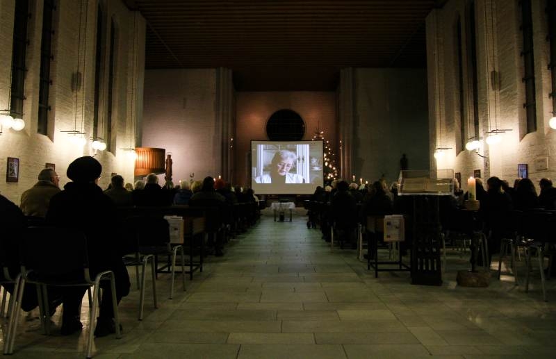 In der Kirche: Der Dokumentarfilm "Der Bunker" auf der Leinwand, die vor dem Altar steht. Alle Bänke sind belegt.