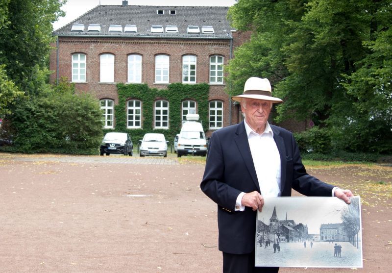 Mit Foto aus den 1920er Jahren: Kurt P. Schneider auf dem Sieglarer Marktplatz vor der Alten Schule.