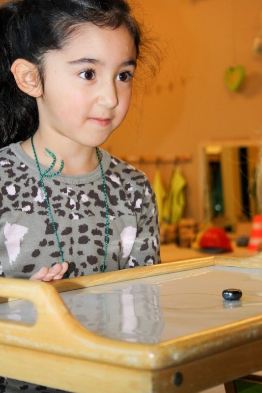 Mit Hilfe eines Magneten muss ein Metallstück über eine vorgezeichnete Linie auf einer Platte bewegt werden.