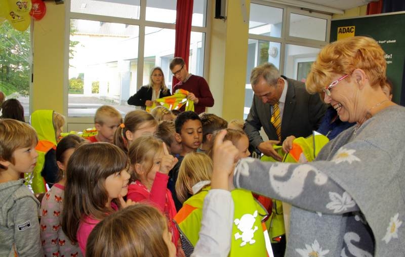 Wolfgang Jakobs (Vorsitzender der Geschäftsführung ADAC Nordrhein), Gisela Kielbassa-Krämer (Schulleiterin) und Gisela Günther (Vize-Bürgermeisterin) helfen den Kindern beim Anziehen der Warnwesten.