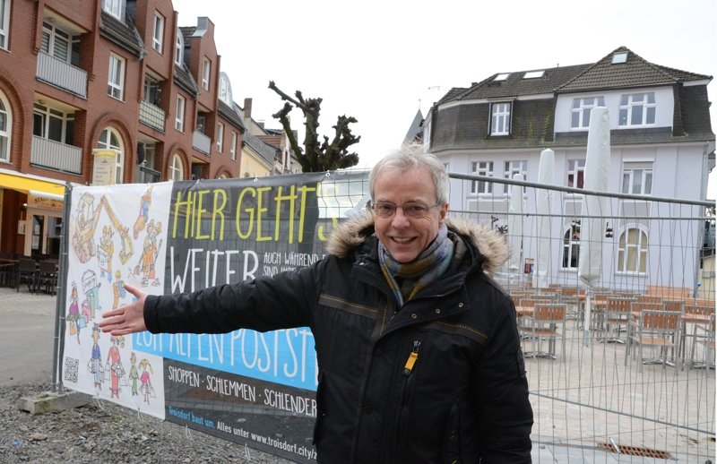 Geschäftsmann Manfred Brenner am Banner zum Hinweis auf die Alte Poststraße.