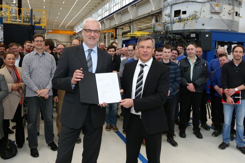 NRW Wirtschaftsminister Garrelt Duin (links) übergibt die EFRE Förderbescheide in Troisdorf an Dr. Wolfgang Kaissl, Geschäftsführer der Varian PT GmbH, vor den Mitarbeiterinnen und Mitarbeitern der Firma.