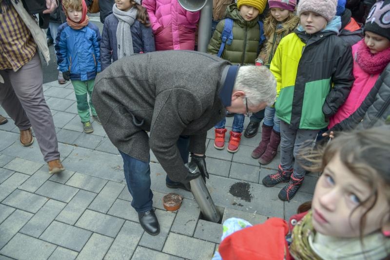 Bürgermeister Klaus-Werner Jablonski versenkt die Zeitkapsel, umringt von Kindern der Grundschule Schlossstraße.