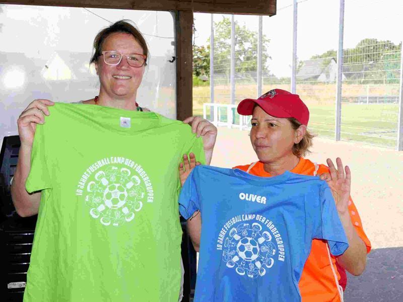 Beate Jäckel (links) und Ayla Koltka zeigen die T-Shirts zu 10 Jahren Fußballcamp.