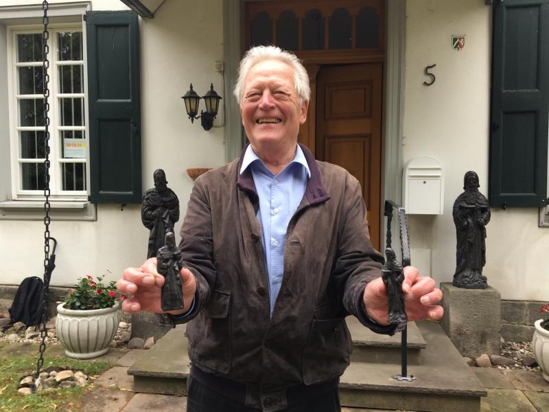 Norbert Königshausen mit den Miniaturstatuen – im Hintergrund die Bronze-Statuen
