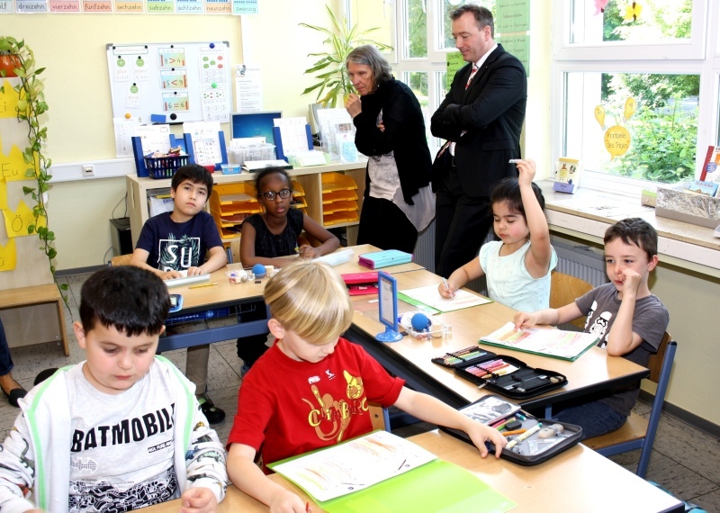 Schulleiterin Petra Zimmermann und Holger Steffens, KSK Köln, schauen den Kindern über die Schulter.