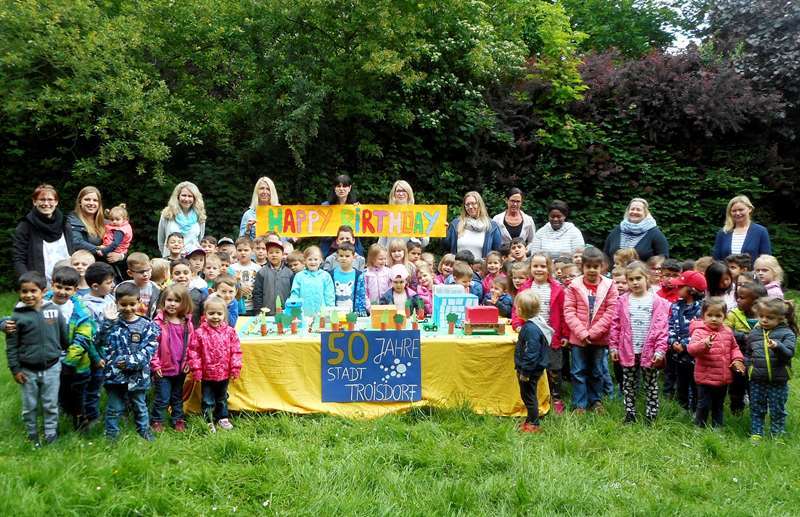Gratulation zum Stadtjubiläum: Kita-Leiterin Sigrid Hafki (Mitte) mit Kindern, Erzieherinnen und dem Stadtmodell.