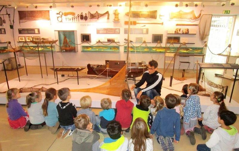 Biologe André Koch erläutert den Kindern die Methoden des Fischfangs.
