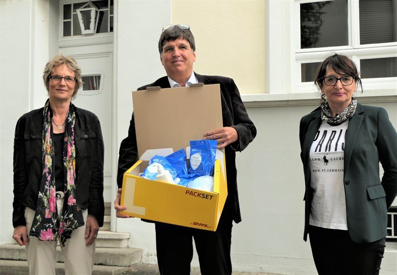 Eine Kiste mit Mund-Nasen-Masken: v.l. Jutta Spoddig, Volker Herdick und Sofia Schulz vor dem SPZ Troisdorf.