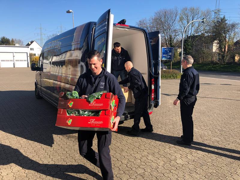 Die Mitarbeiter der Feuerwehr tragen die Lebensmittelspende in die Feuerwache