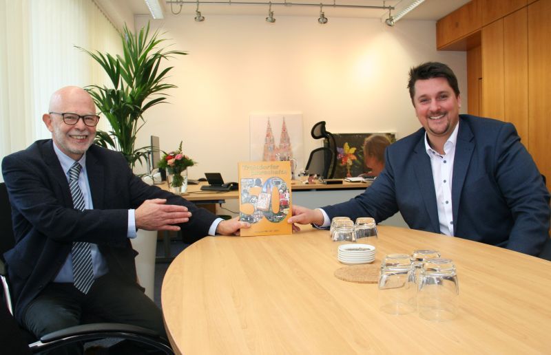 Claus Chrispeels übergibt Bürgermeister Alexander Biber das neue Troisdorfer Jahresheft.