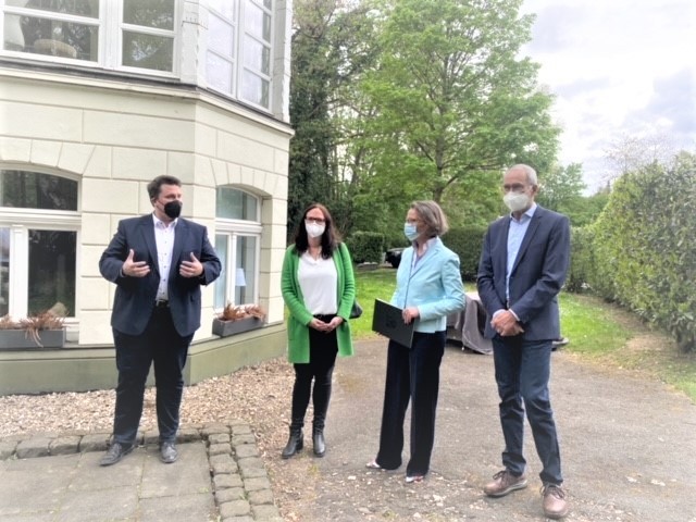 Bürgermeister Biber, MdL Gebauer, Ministerin Scharrenbach und Ortsvorsteher Eich vor Villa Langen.jpg