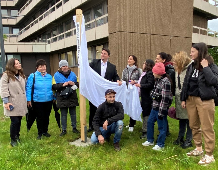 Bürgermeister Alexander Biber enthüllt mit Unterstützung von Geflüchteten aus der Ukraine einen Friedespfahl für Troisdorf.  