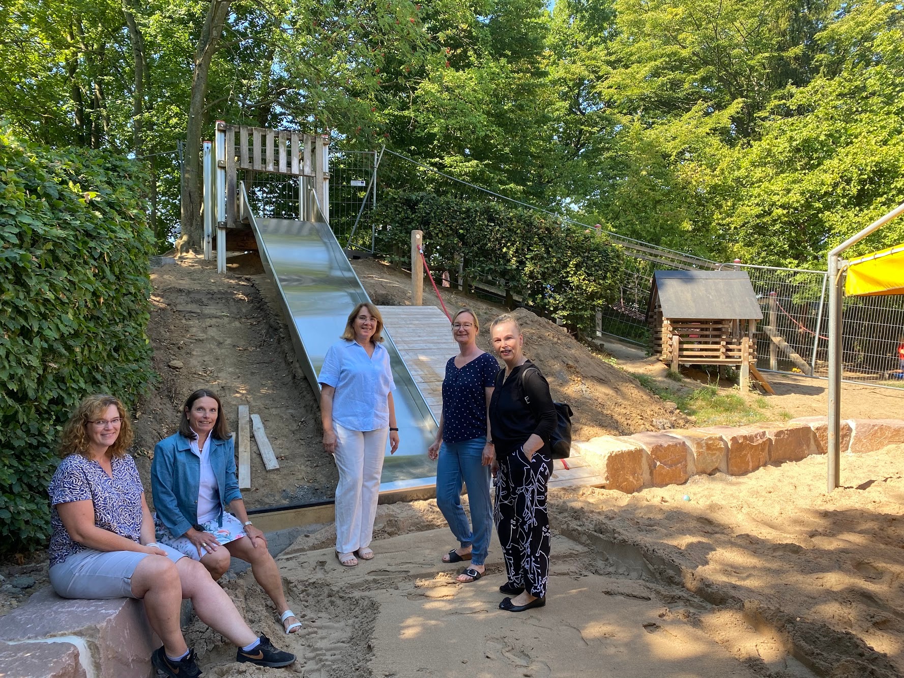 Kita-Leiterin Claudia Lasseur-Au (mitte), ihre Stellvertreterin Martina Assenmacher-Klein (2. v. r.), sowie aus dem Rathaus die Beigeordnete Tanja Gaspers (2. v. l.), Sabine Streeck (r.) und Martina Neuer (l.) begutachten den Baufortschritt auf dem Spielgelände der Kita Flachtenstraße und besprechen künftige Projekte. 