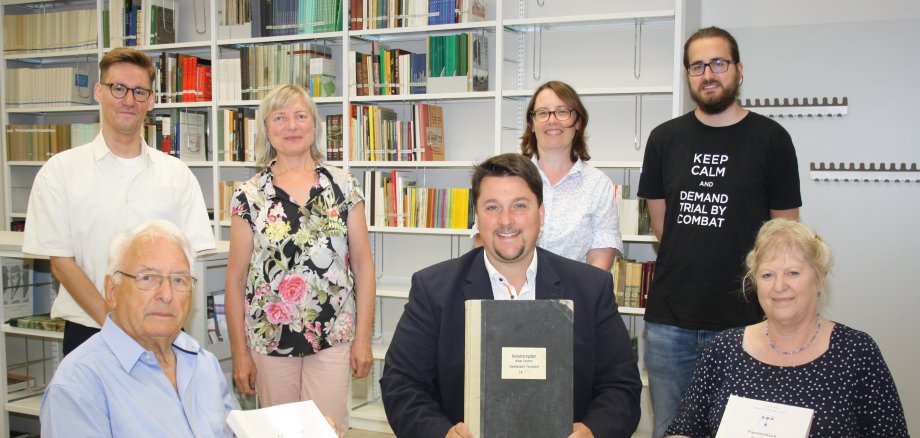 Heribert Müller und Waltraud Boß mit Bürgermeister Biber vor dem Team des Stadtarchivs.