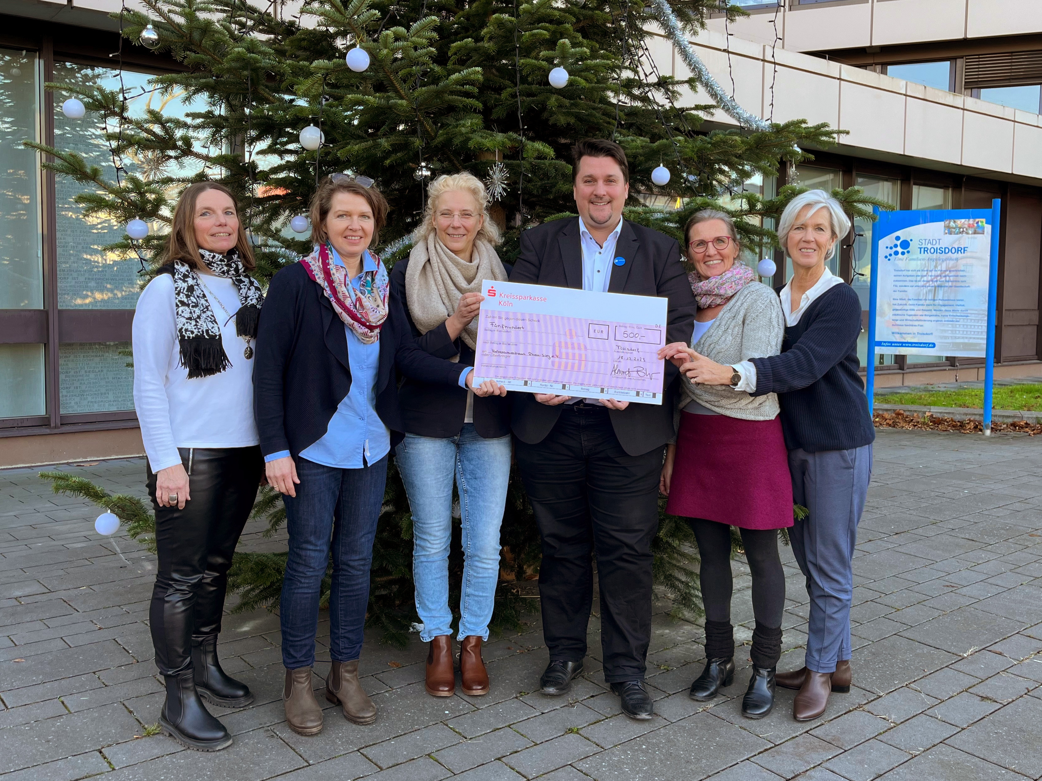 Bürgermeister Biber mit Spendenscheck eingerahmt von fünf Frauen.