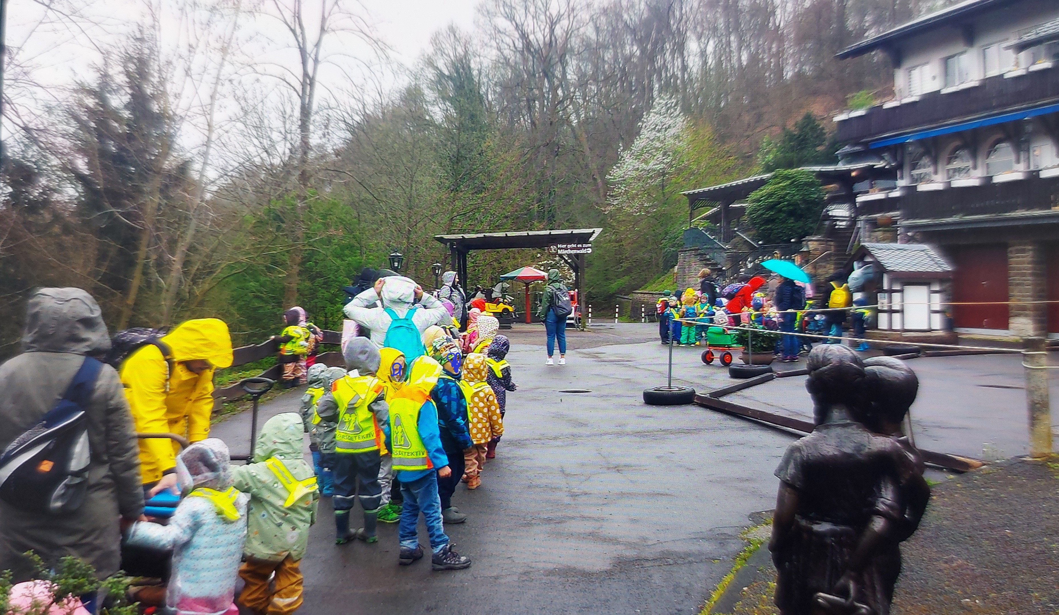 Kinder und Erzieherinnen in Regensachen vor dem Märchenwald