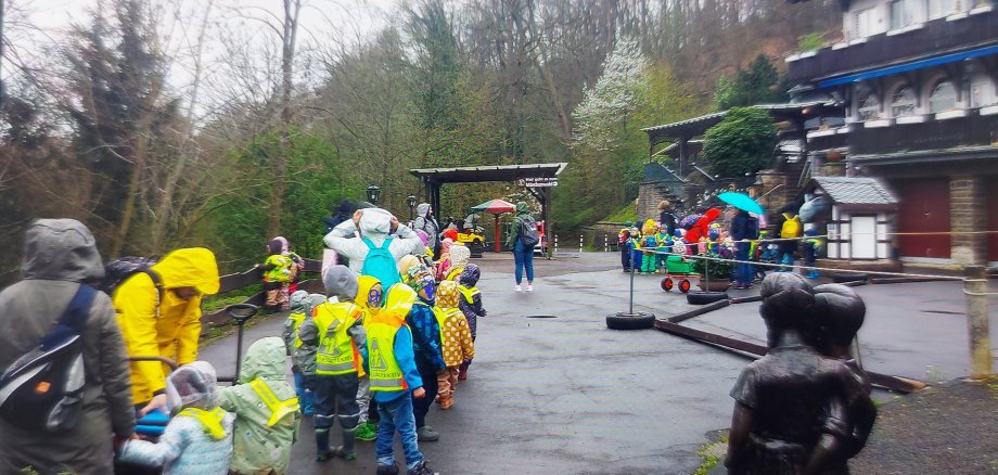 Kinder und Erzieherinnen in Regensachen vor dem Märchenwald