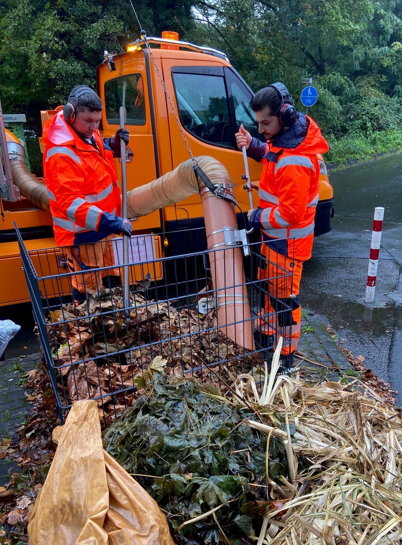 Mit einem Saugrohr werden die Laubkörbe von Bauhofmitarbeitenden entleert. 