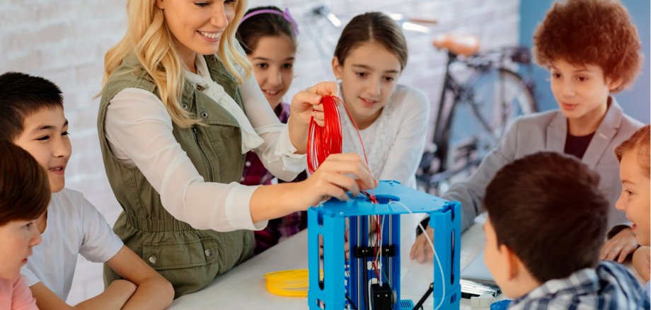 Kinder mit einer Frau am 3D-Drucker