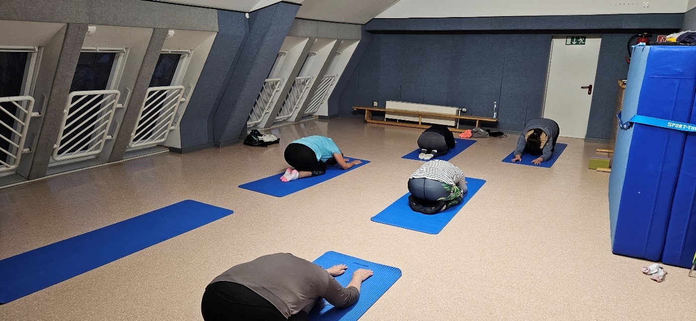 Teilnehmer*innen am Yoga-Kurs in der Haltung des Kindes