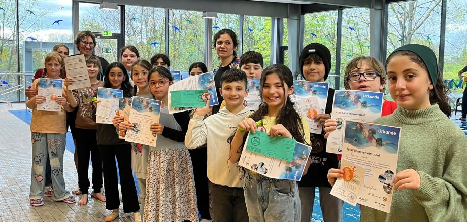 Stolz halten die Troisdorfer Grundschulkinder ihre Schwimmabzeichen in den Händen, die sie während der Osterferien im Rahmen des Landesprogrammes „NRW kann schwimmen! Schwimmen lernen in den Schulferien in NRW!“ erfolgreich erworben hatten.