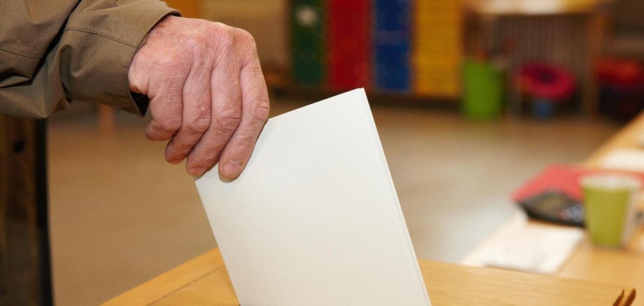 Stimmzettel wird in Urne geworfen