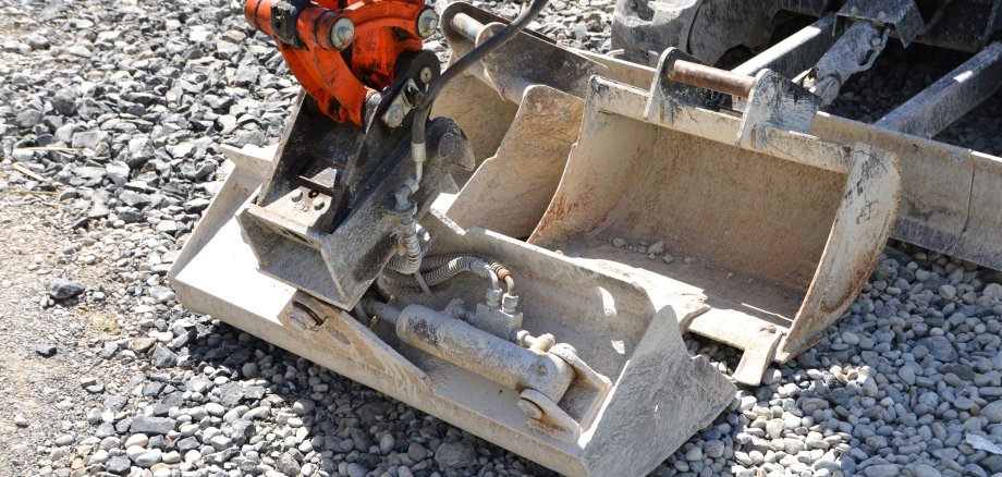 Bagger mit Schaufel auf Pflastersteinen