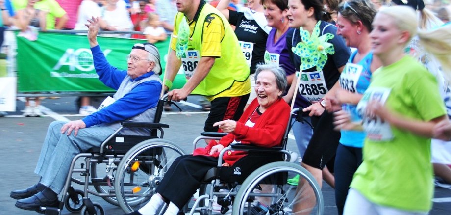 Zwei Senior*innen im Rollstuhl bei einem Lauf