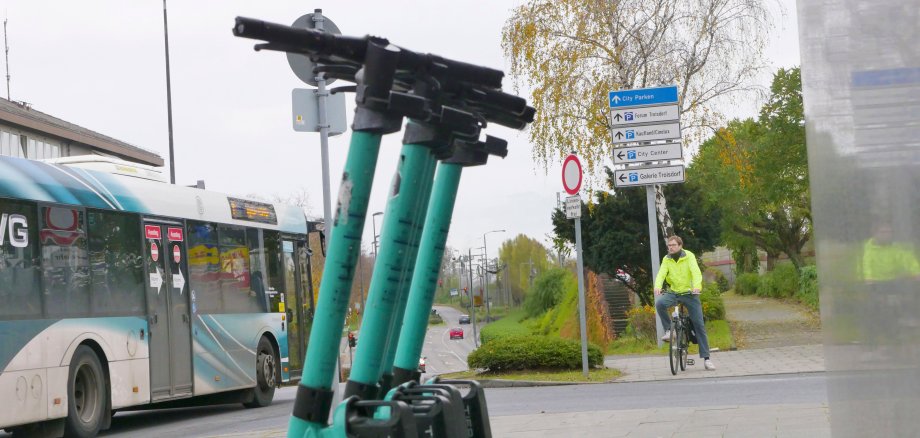 E-Roller, ein, Bus, ein Radfahrer, im Huntergrund ein Park and Ride System und Autos.